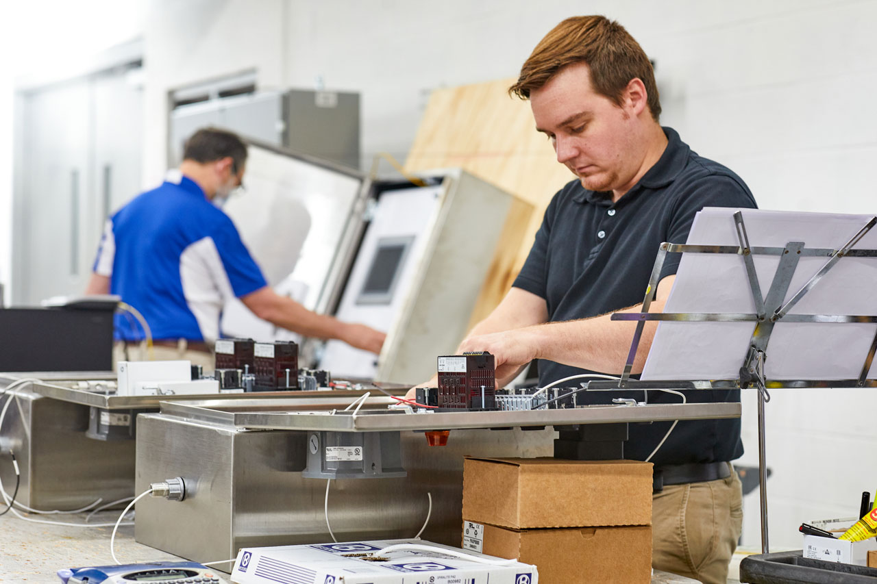 man with red hair assembling a control board for an industrial automation system