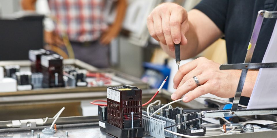 two male hands adjusting components of a mechanical control board with wires