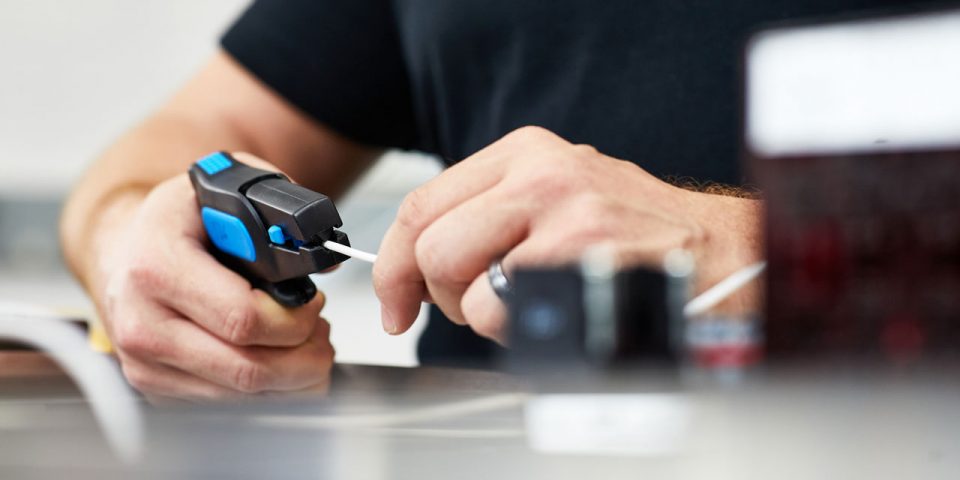 two male hands using a tool to cut a wire