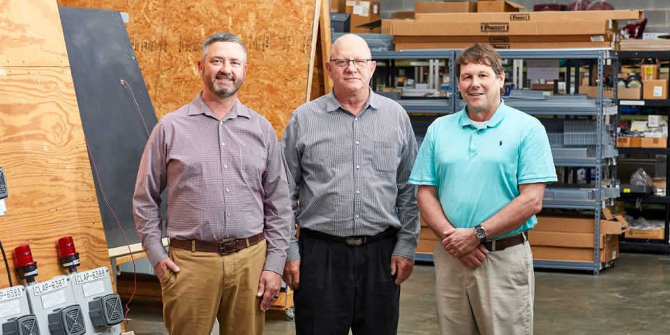 three smiling male employees in the warehouse of Lord & Company Industrial Automation